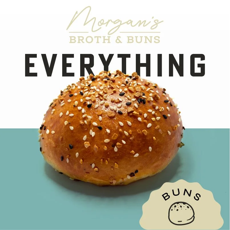 A bread bun topped with sesame and black seeds on a pastel background, with text overlay promoting Morgan's Broth & Buns and their slogan 'Everything Buns'.