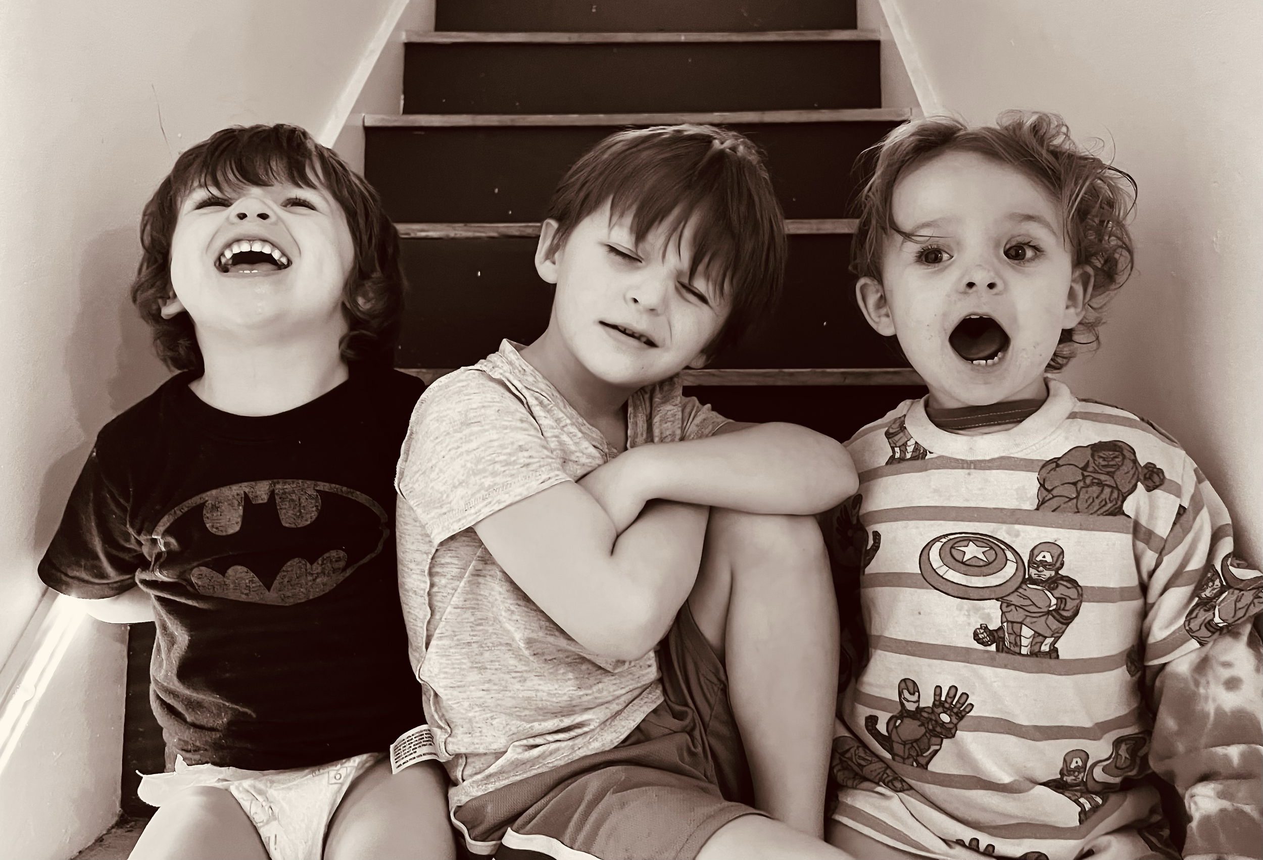 Three young children sitting on stairs, with varied facial expressions.