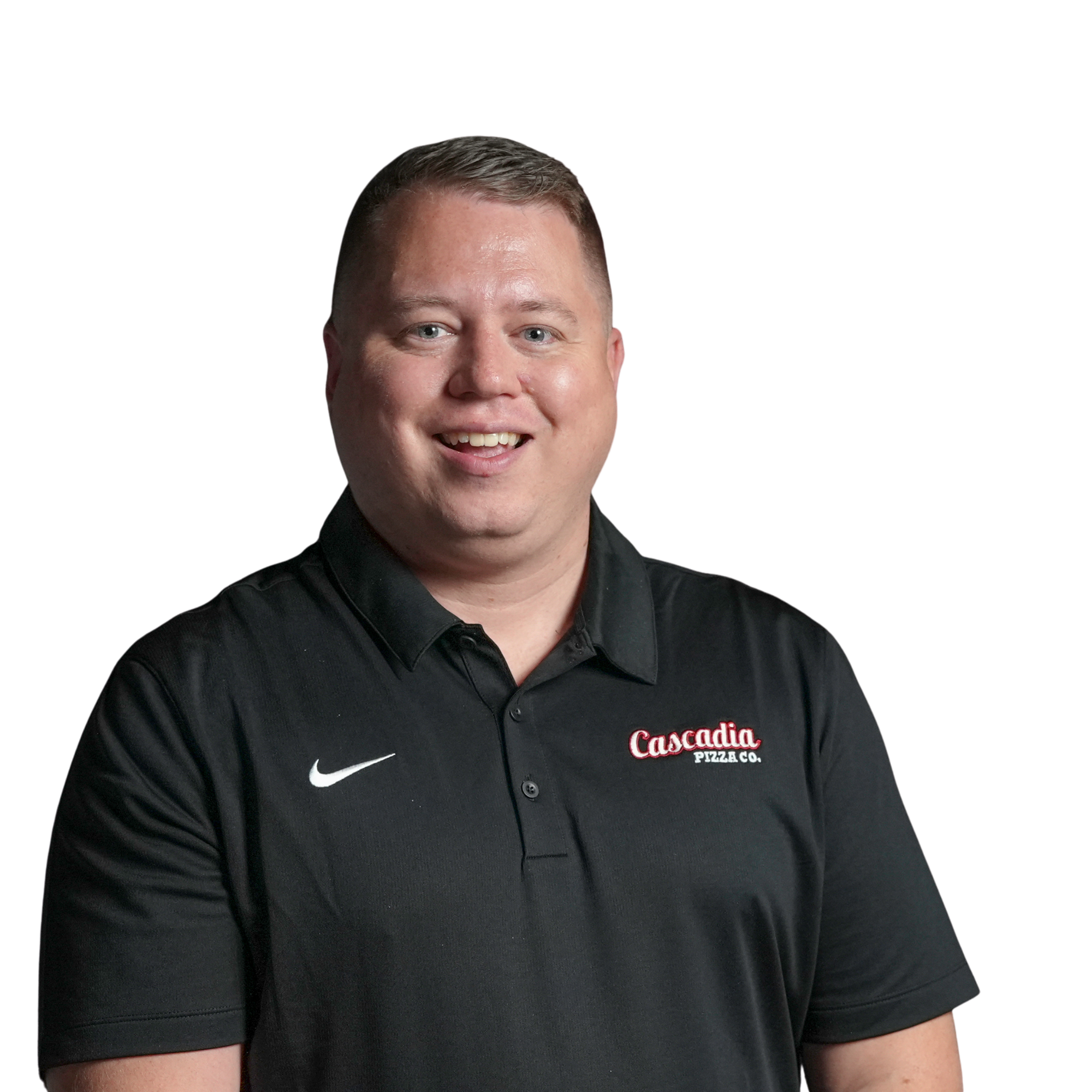 Close-up of a smiling man in a black collared shirt with 'Cascadia Pizza Co.' logo, against a black background.