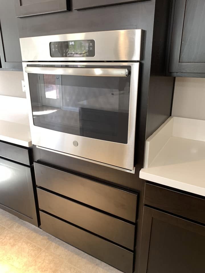 Stainless steel wall oven built into dark cabinetry with three drawers below.