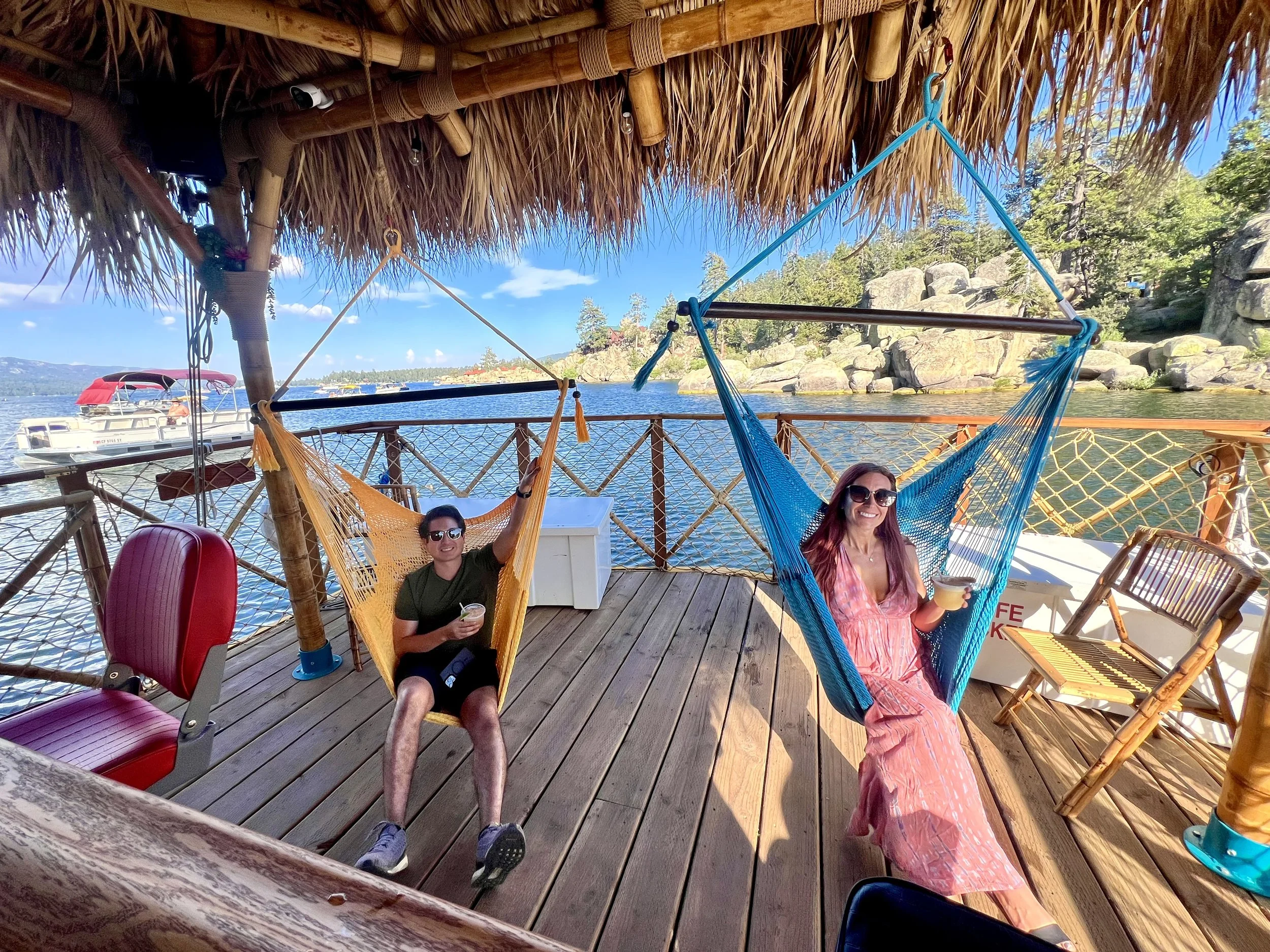 Two people smiling and sitting in hammocks on the Big Bear Tiki Tours boat