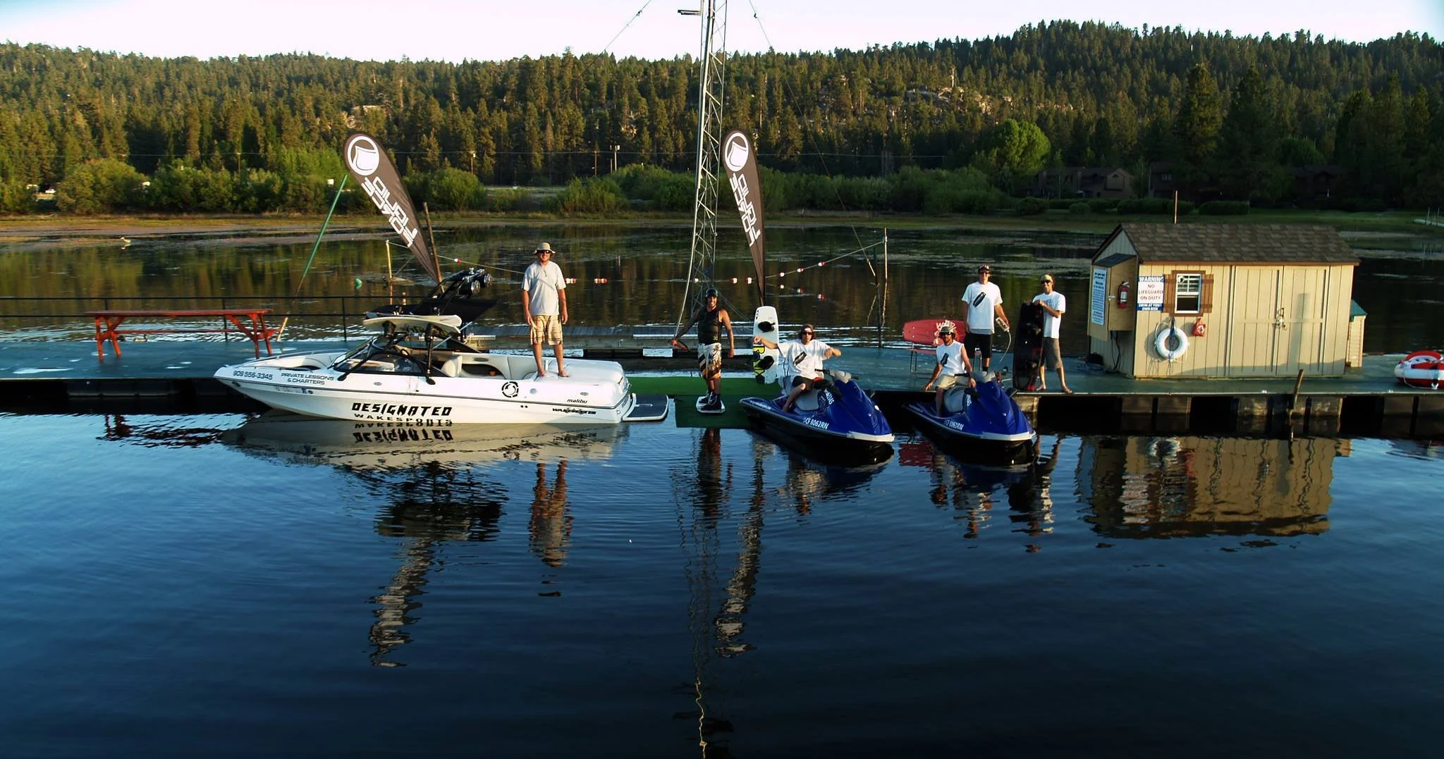 Two jet skis and a wake boat on the dock on Big Bear Lake with staff waiting to provide guests a good time