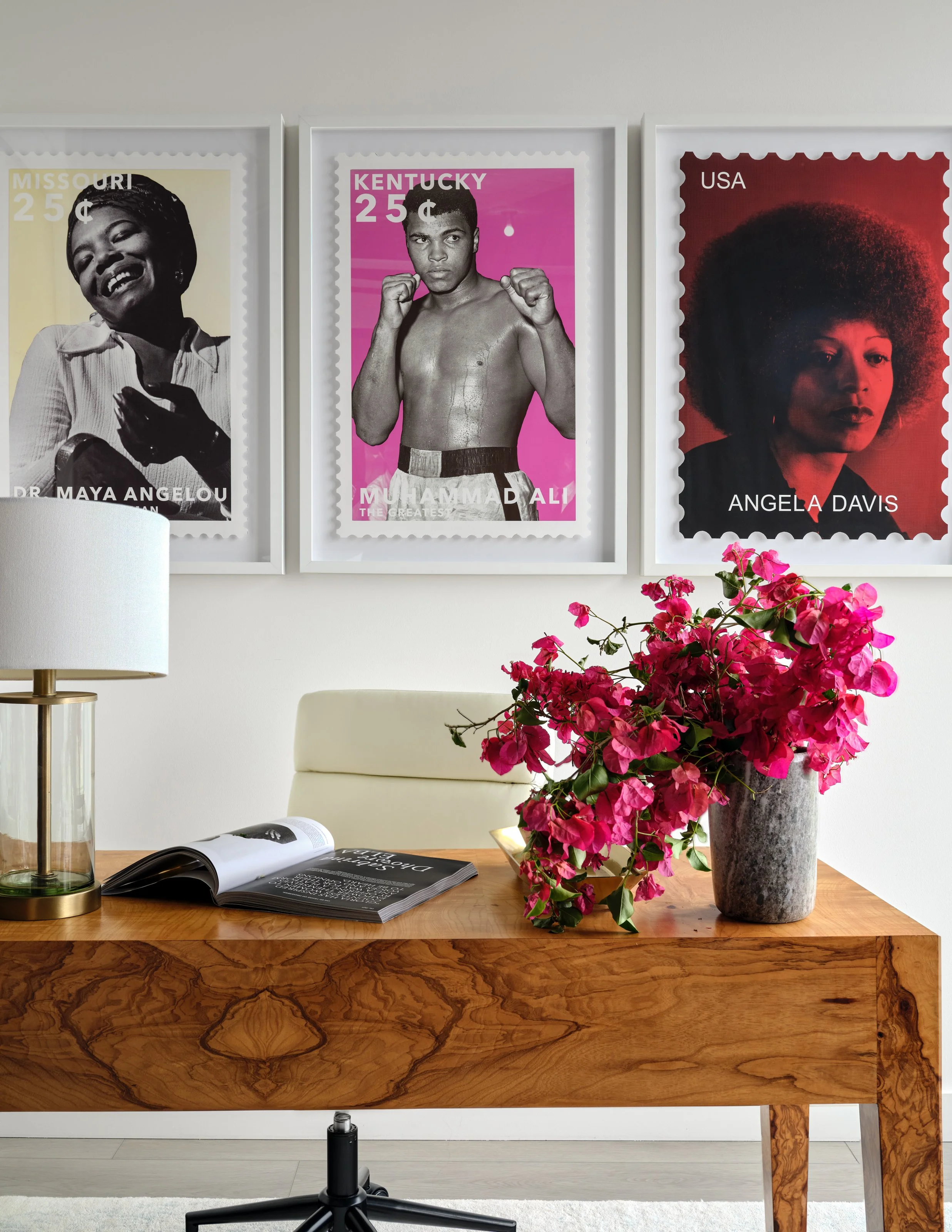 A celebration of culture and creativity gives this home office its distinct personality. Iconic portraits create a bold gallery wall above the richly grained wood desk, while vibrant florals and refined brass accents bring warmth, color, and energy t