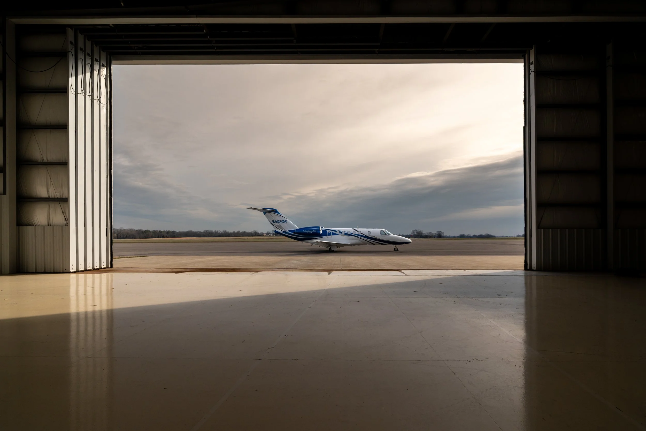 A small private jet parked outside a hangar on an overcast day.