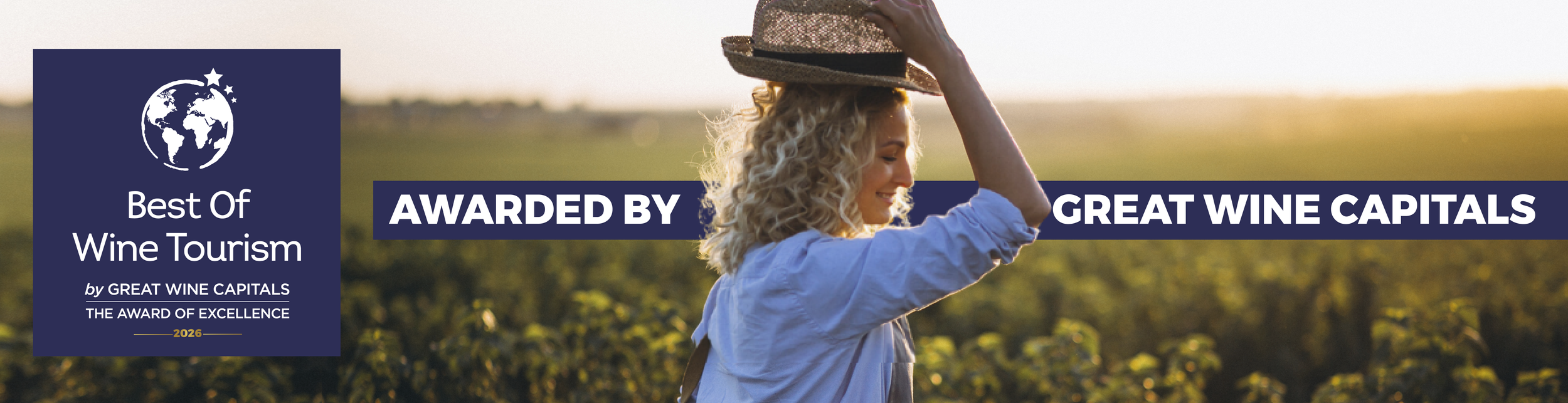 Best of Wine tourism award logo in front of sunset vineyard with woman side profile lifting hat