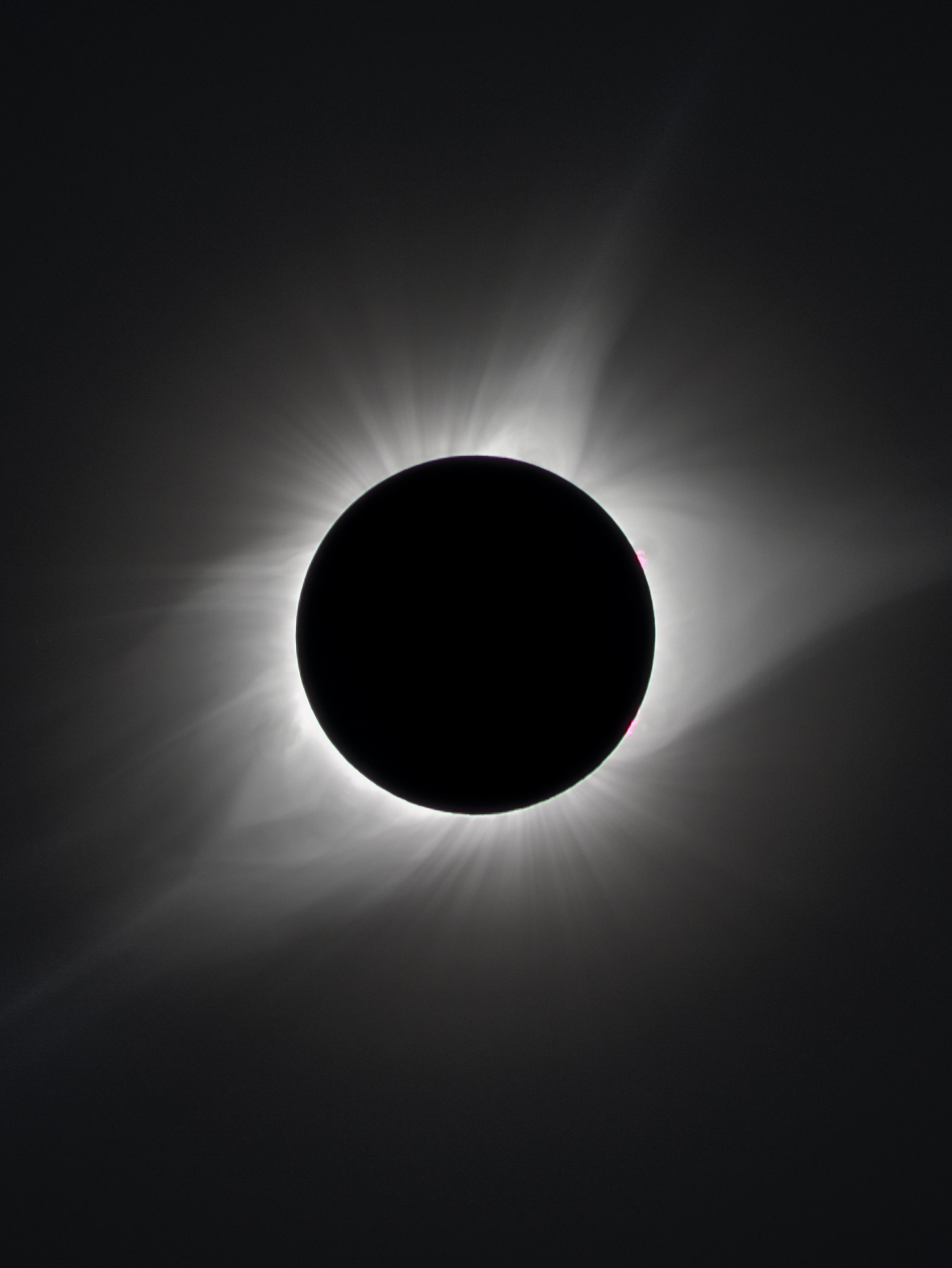 Solar eclipse with the moon covering the sun, creating a dark silhouette with solar corona rays visible around the edges.