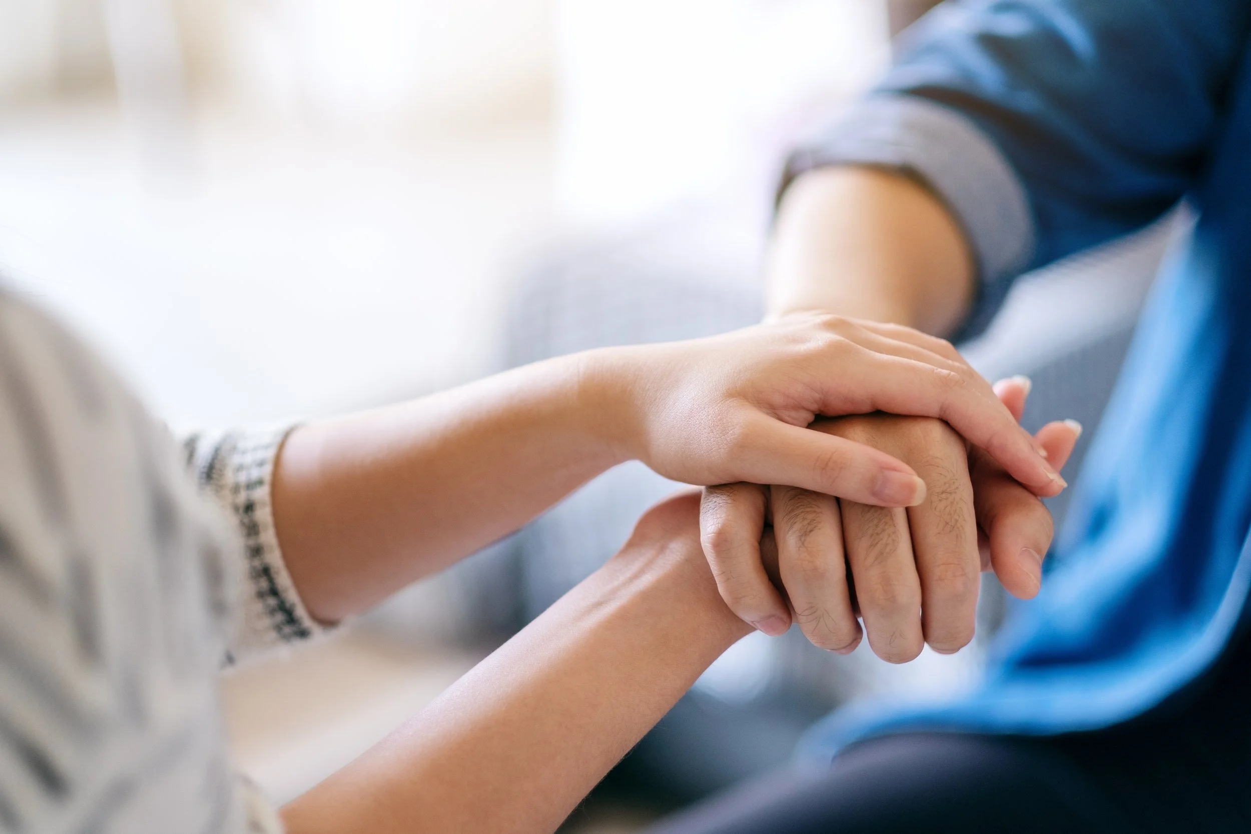 Close up of a caregiver's hands embracing the hand of a care recipient.