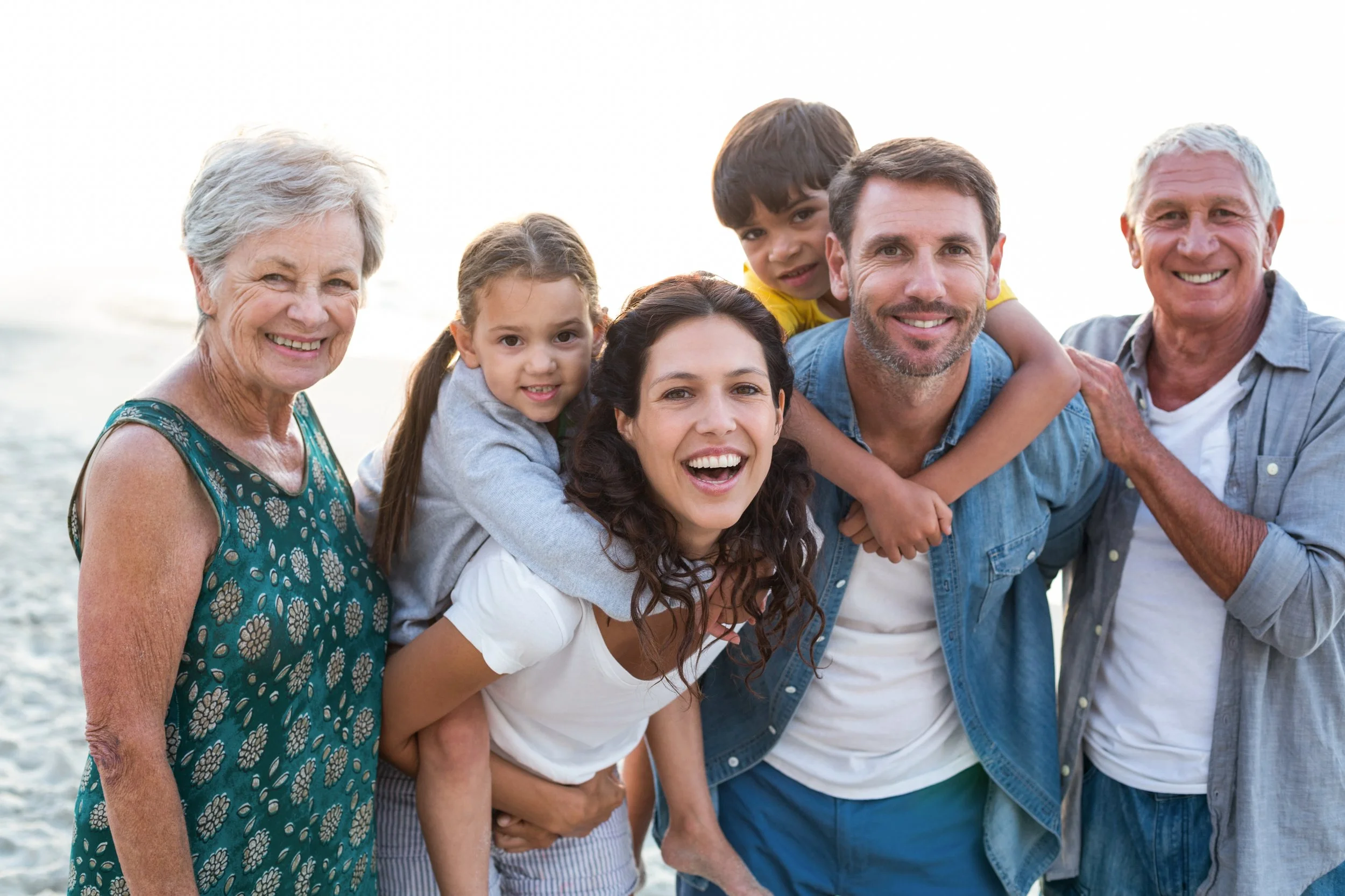 Family on a white background, everyone is smiling and looking at the camera.