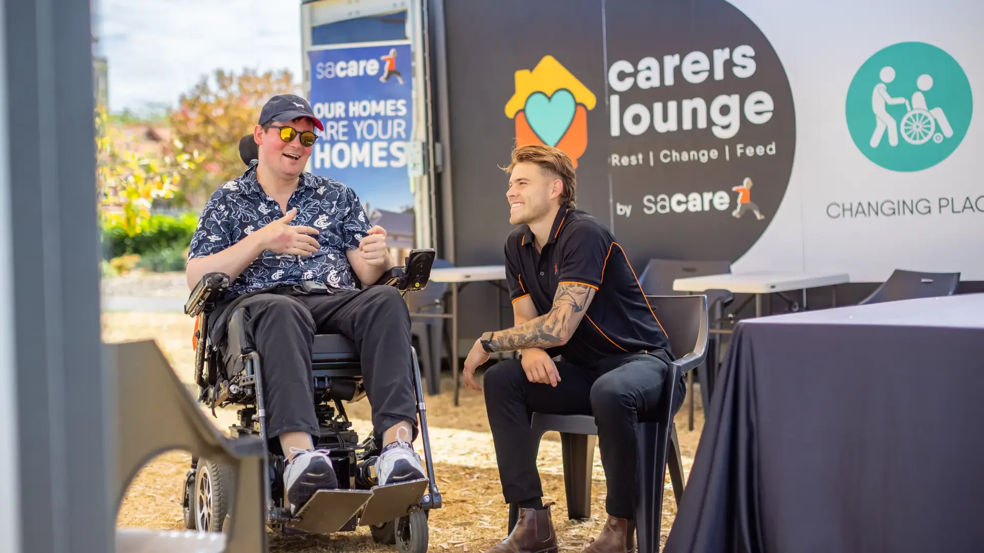 Person using a wheelchair talking with another person at a carers lounge event