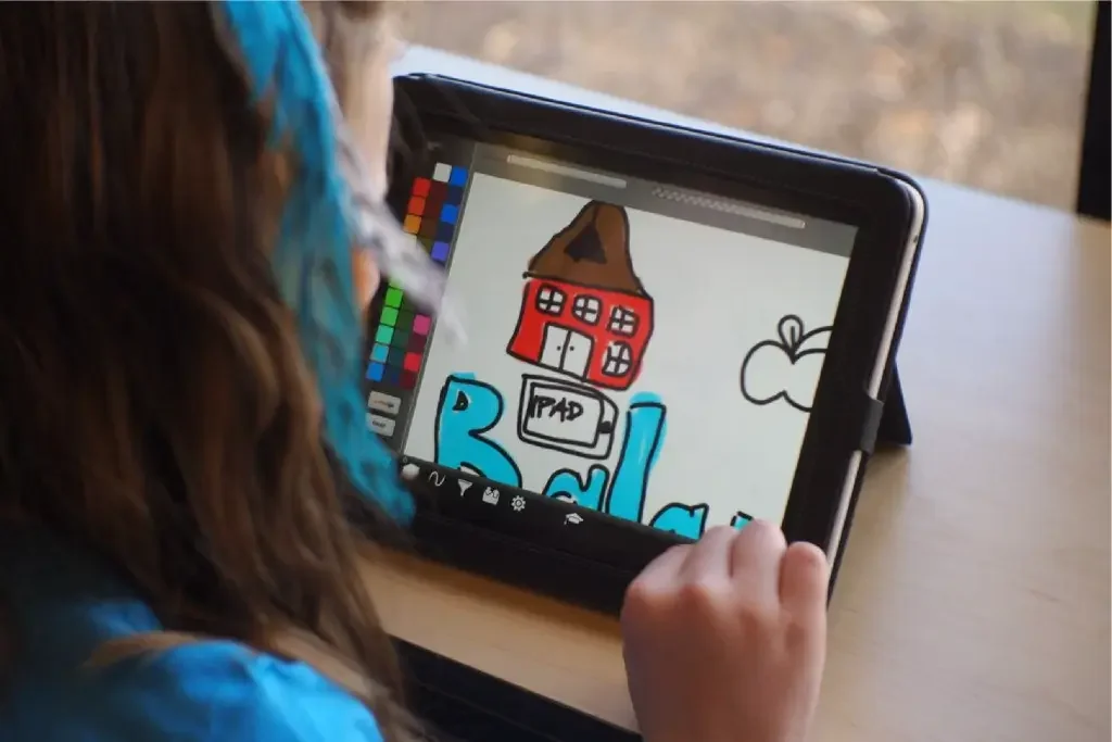 Child drawing colourful house illustration on tablet device.