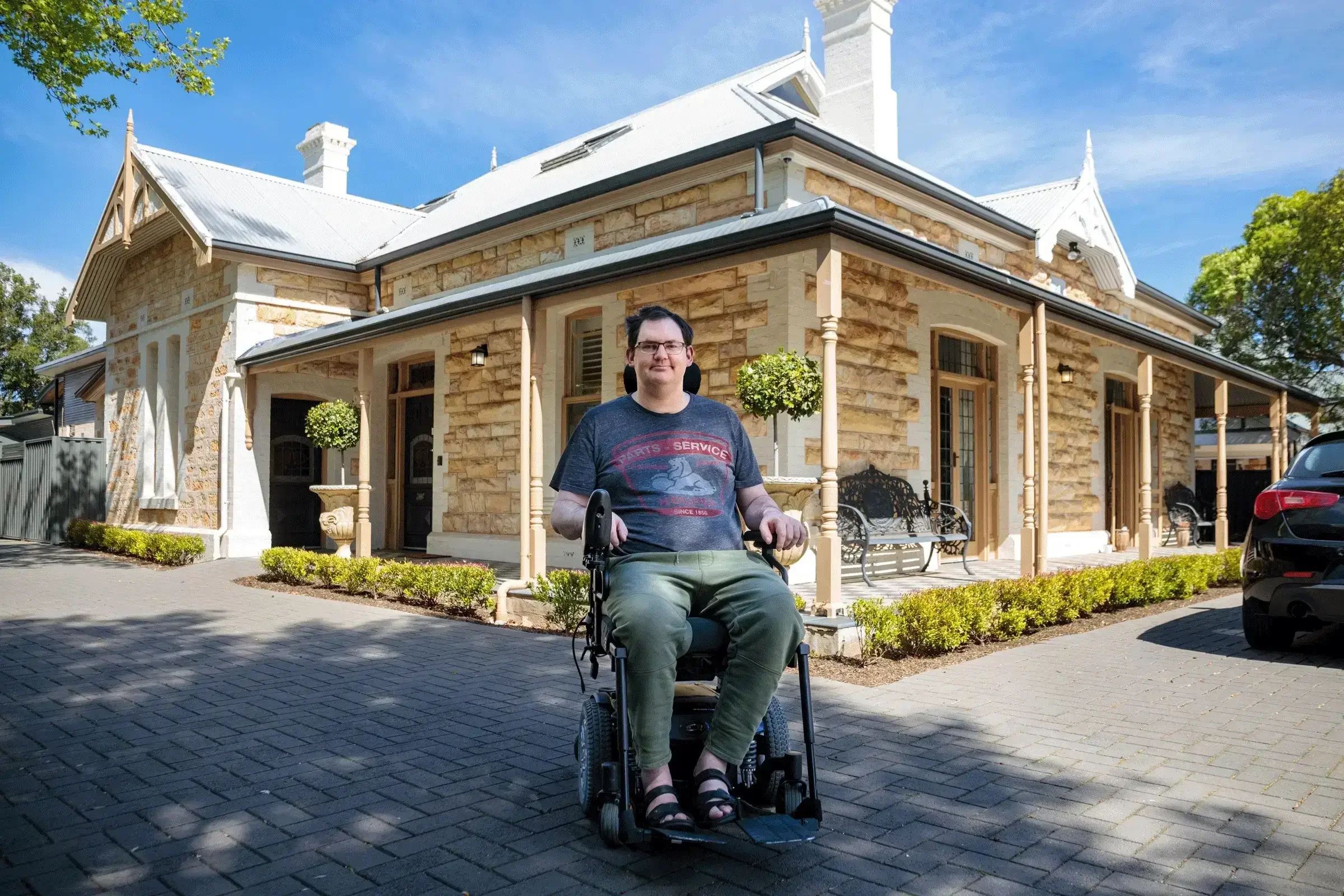 Wheelchair user outside accessible supported accommodation residence.