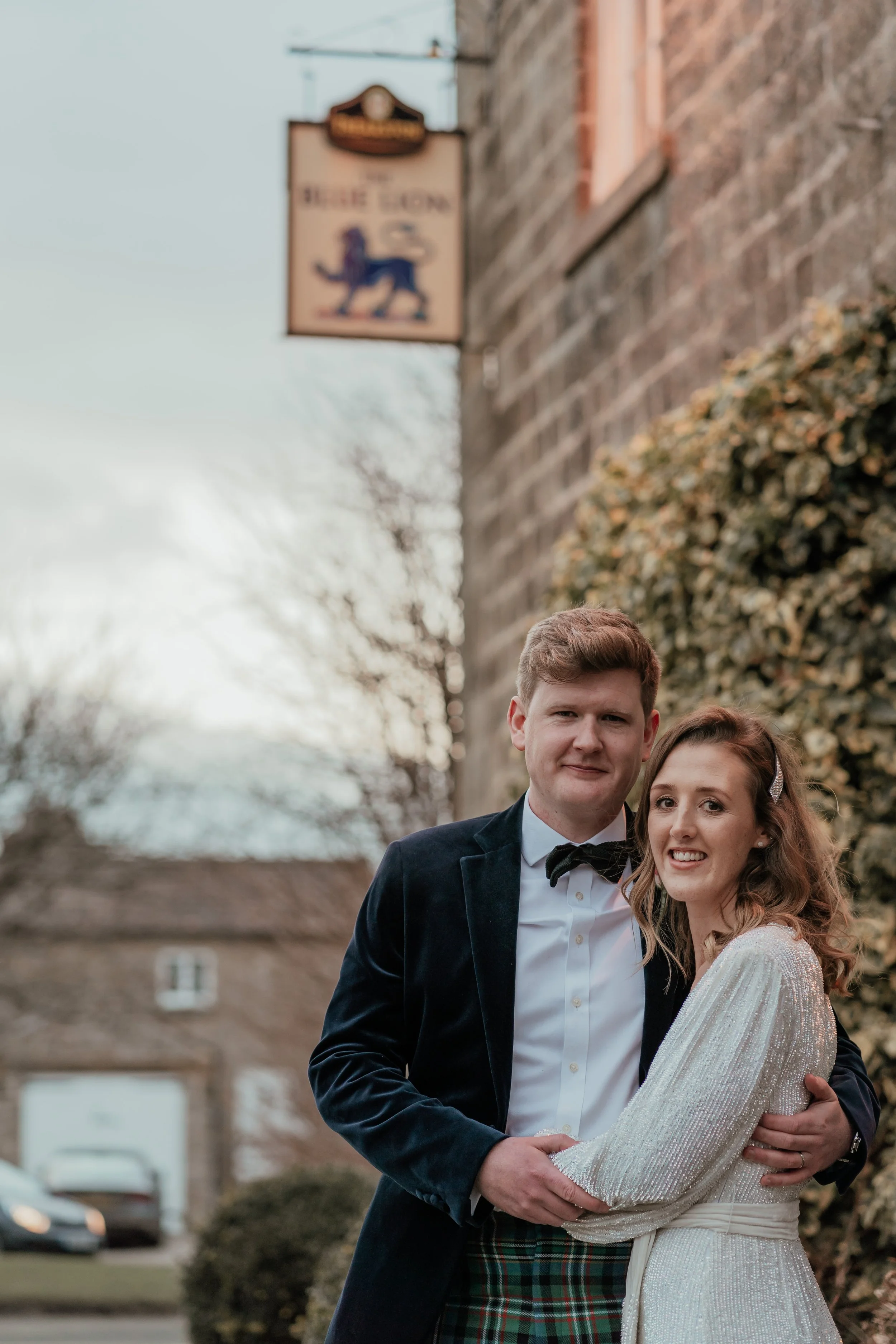bride & groom embracing outside the sign for The Blue Lion Pub, Yorkshire