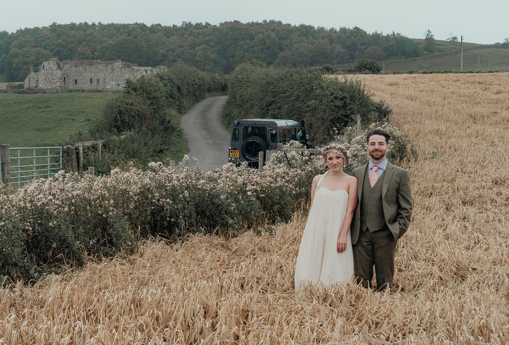 bride and groom in cornfield with defender landrover