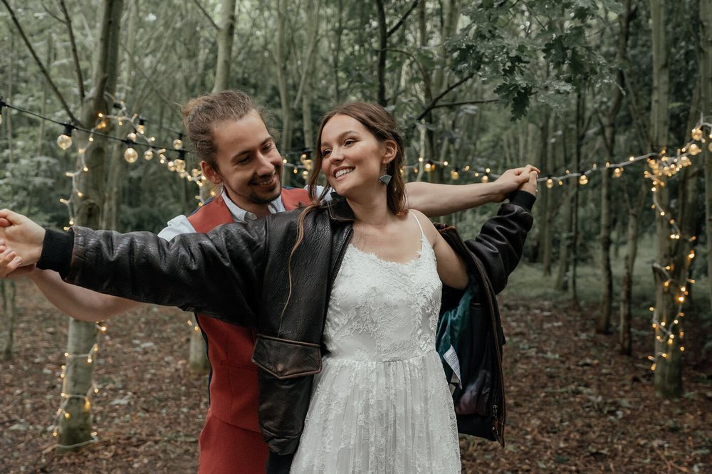 alternative bride with leather jacket with groom in woodland wedding