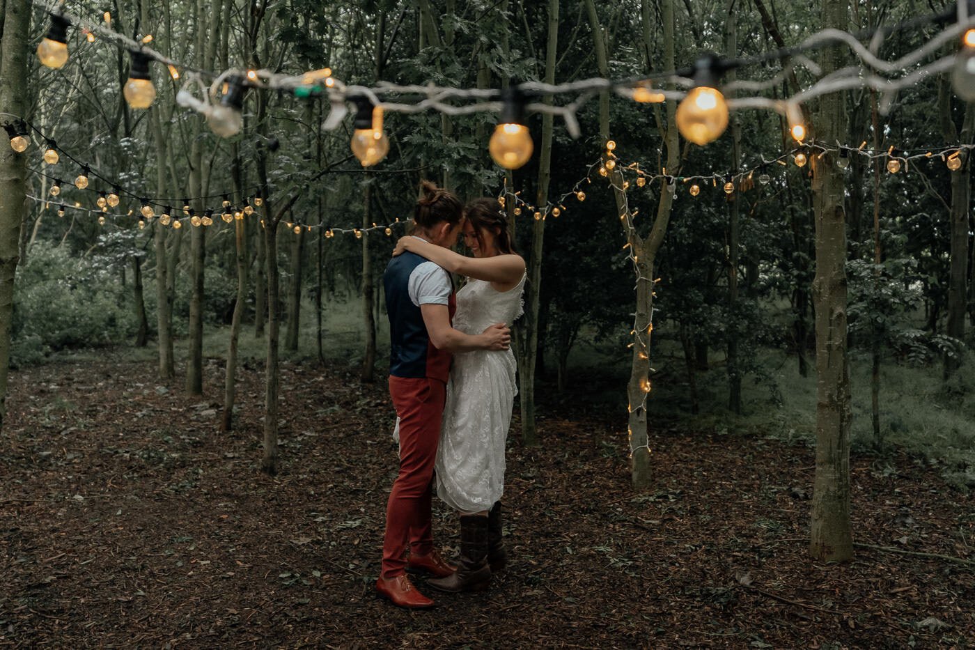 first dance for wedding couple in forest with festoon lighting