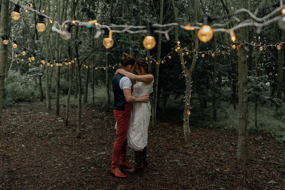 first dance for wedding couple in forest with festoon lighting