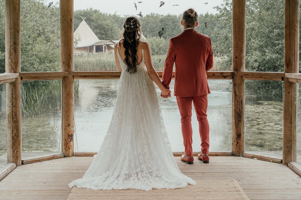 bride and groom look out over lake at tipi wedding