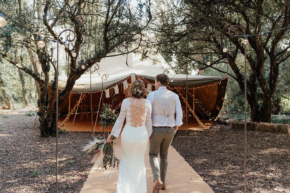 bride and groom make an entrance at their woodland tipi wedding