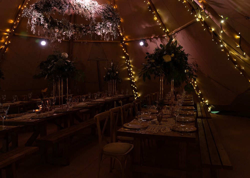 boho styled tipi at night with fairy lights covering the columns