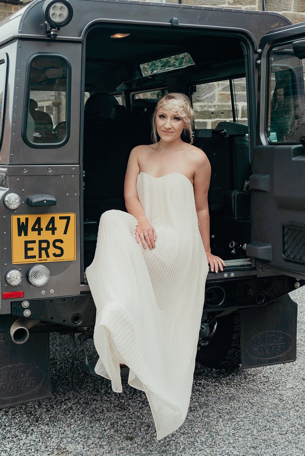bride in simple wedding dress in the back of a landrover defender