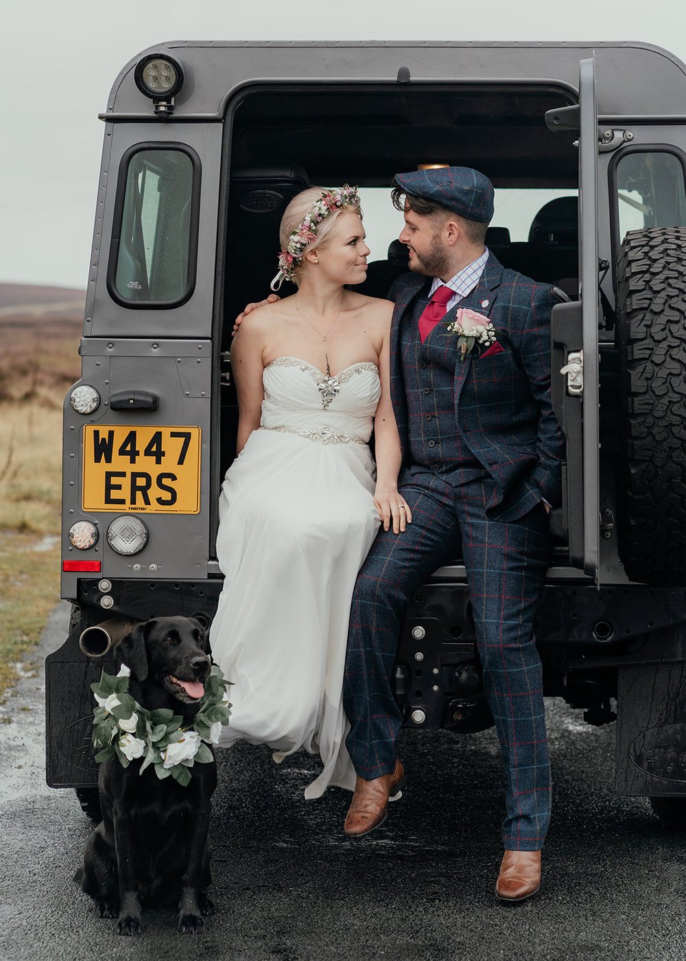 bride and groom in the back of a landrover defender with dog at wedding