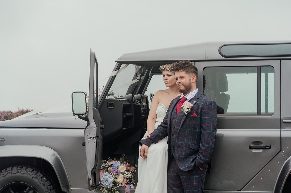 countryside flowers and tweed suit with landrover defender wedding car