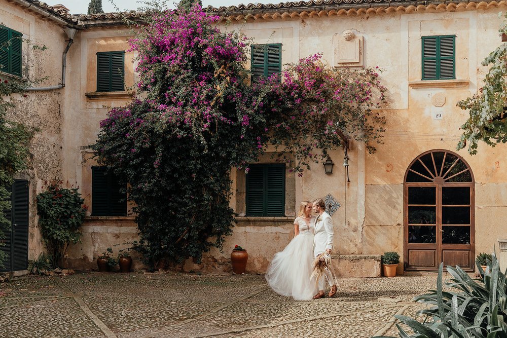 mallorcan rustic finca wedding venue courtyard with tropical flowers and kissing couple