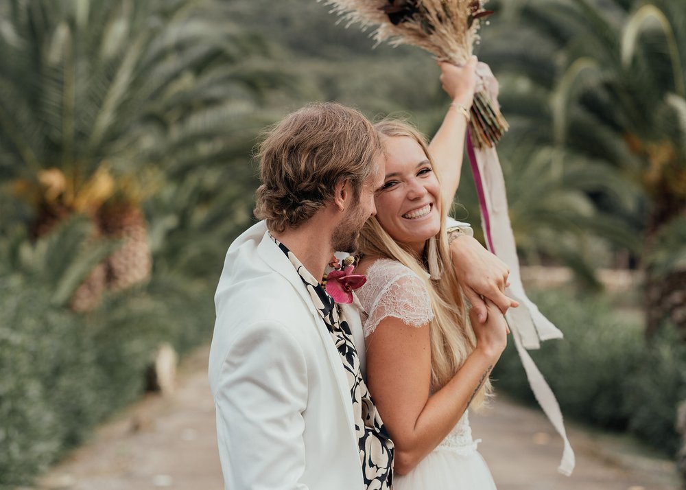 wedding celebration with palm trees as bride throws bouquet into the air