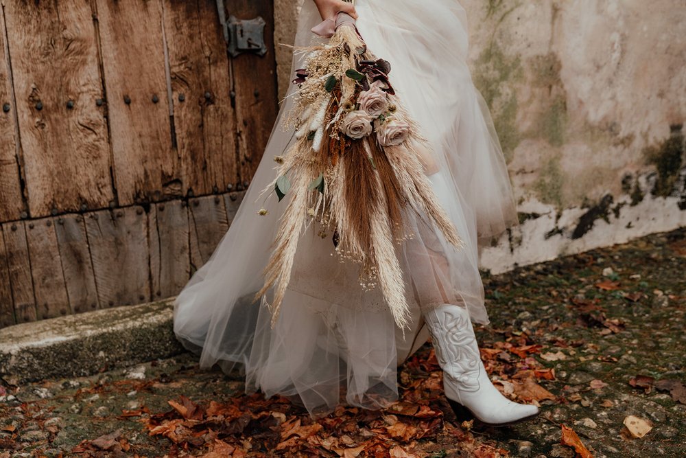 cowboy boots with wedding dress and dried floral bridal bouquet