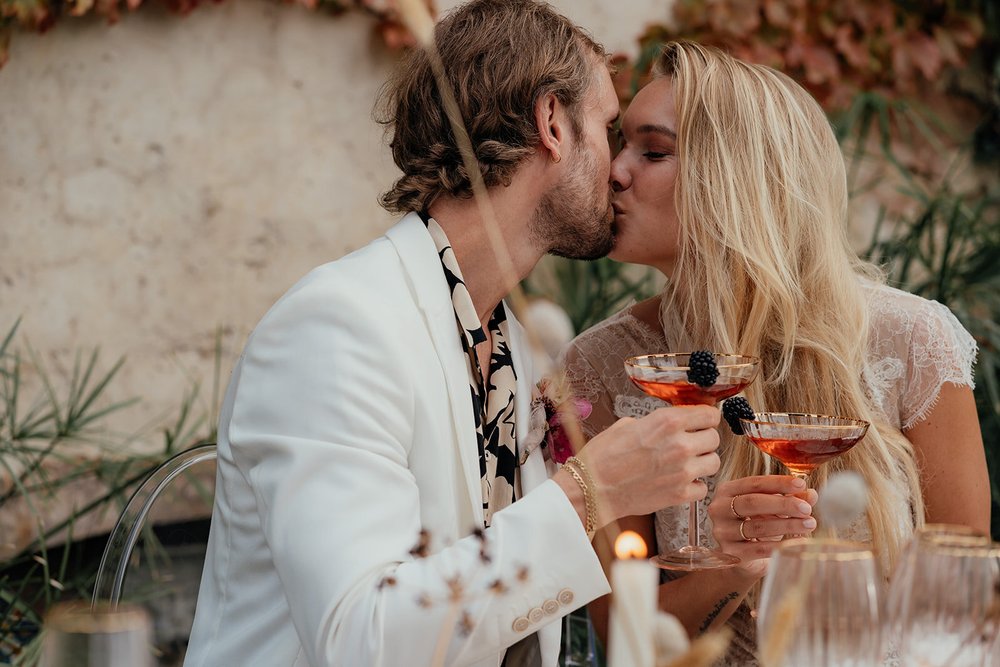 couple kissing with cocktails in mallorcan garden wedding venue