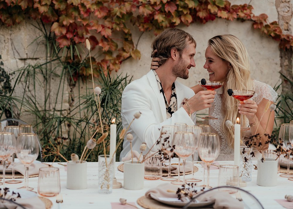 bride and groom with cocktails in front of autumnal ivy