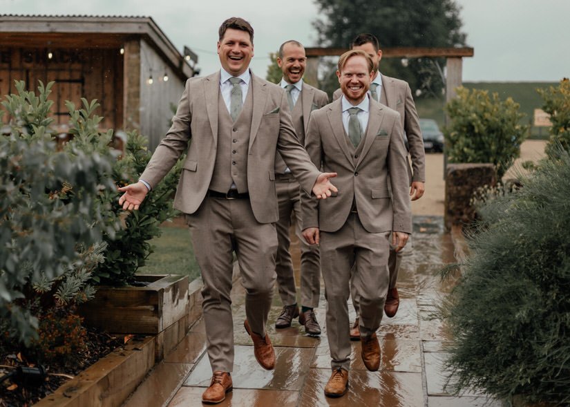 groomsmen walking in the rain into a wedding