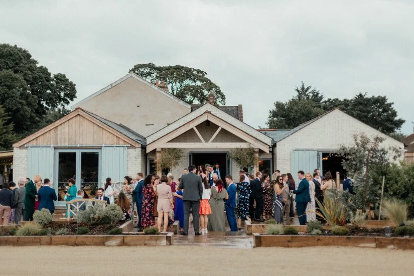panoramic view of Eden Barn wedding venue from the outside with guests in front