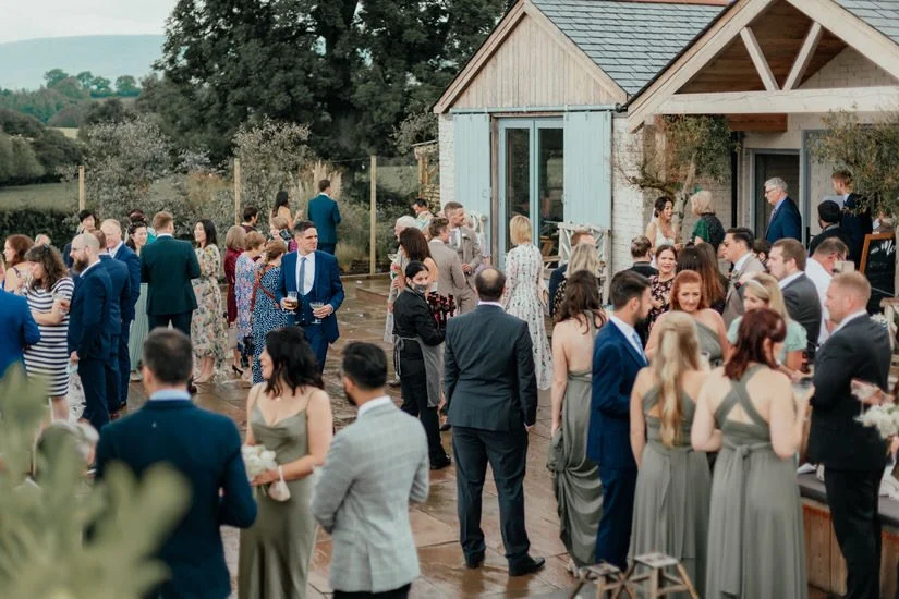 wedding guests at a drinks reception outside Eden Barn