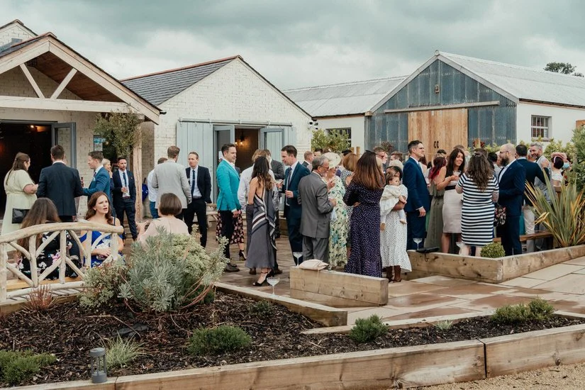 wedding guests at a drinks reception outdoors at Eden Barn wedding venue