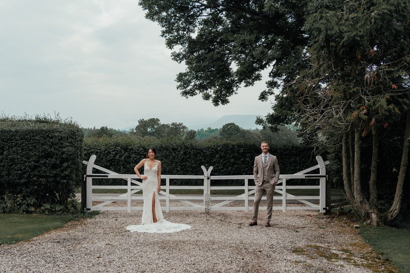 bride and groom standing in front of a white gate on a driveway