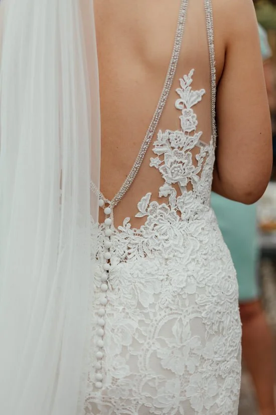 back of a bride's lace dress with her veil on as well
