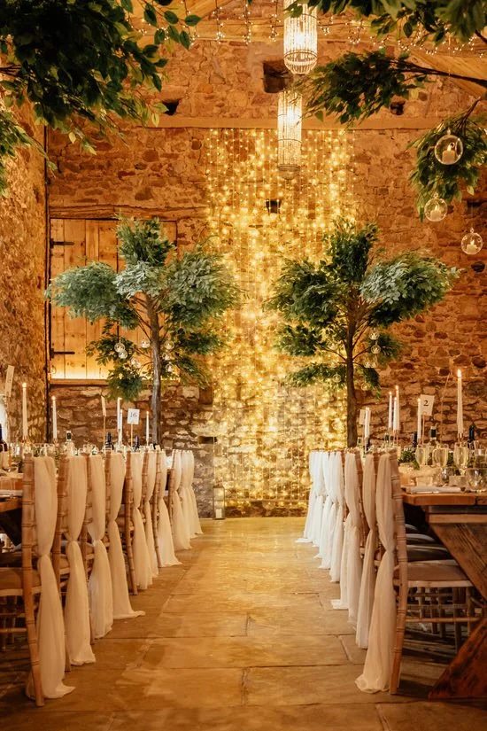 wedding barn set up for a wedding breakfast with trestle tables and indoor trees