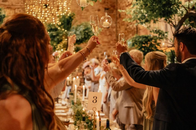 guests cheering glasses together at a wedding speech