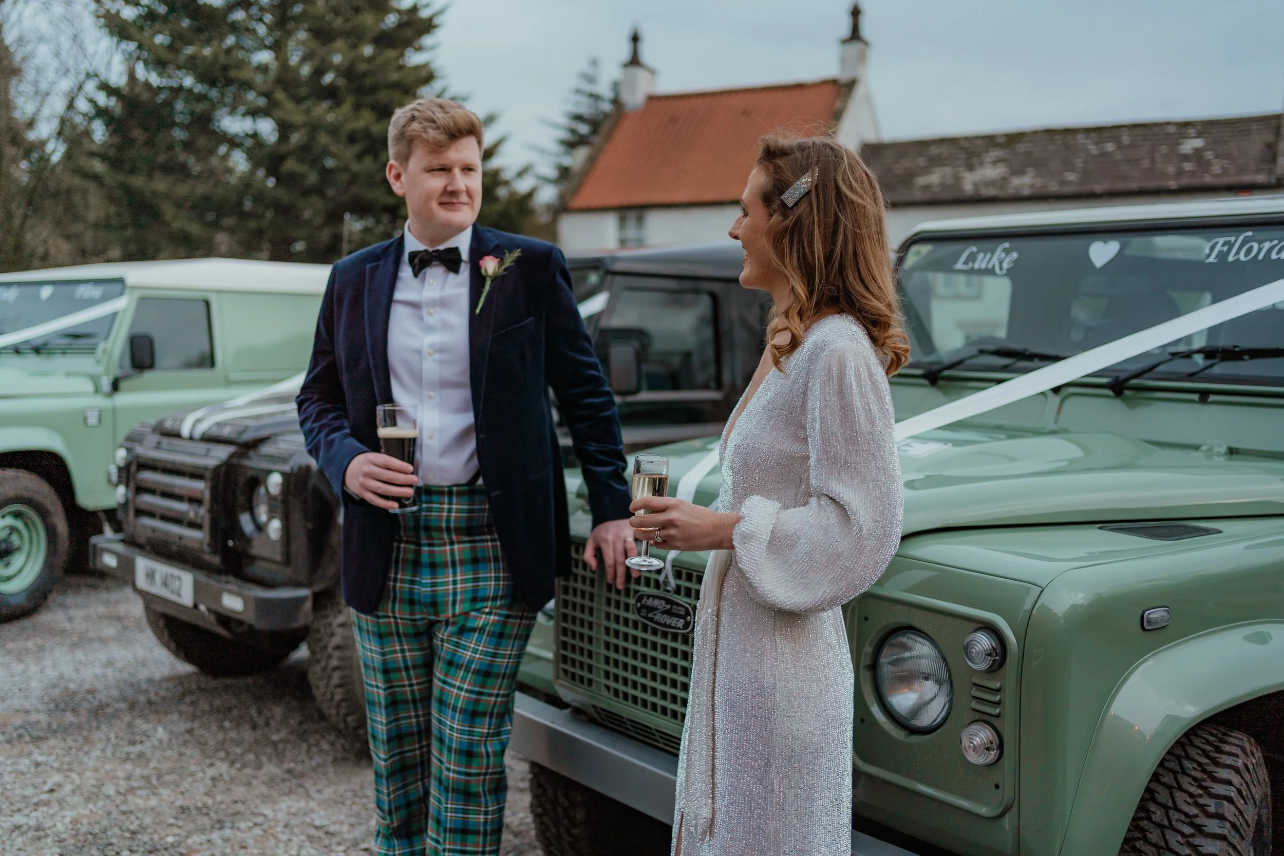 bride & groom leaning on a pale green Landrover Defender outside The Blue Lion pub Yorkshire