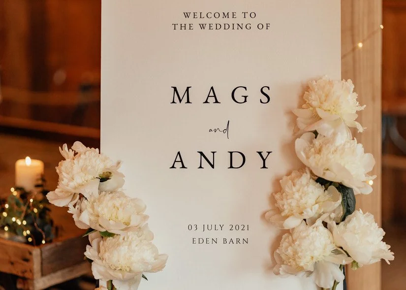 wedding welcome sign in white with black writing and peony decorations