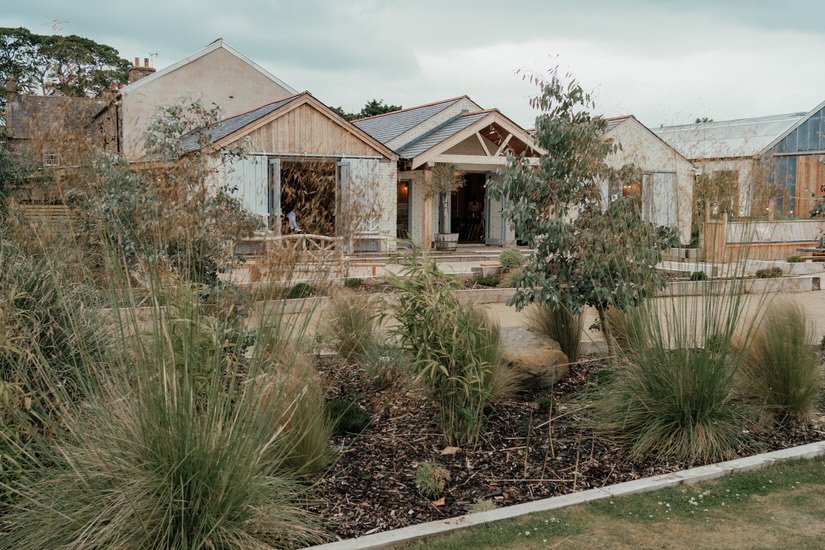 outdoor area of Eden Barn wedding venue showing the gardens and barn itself