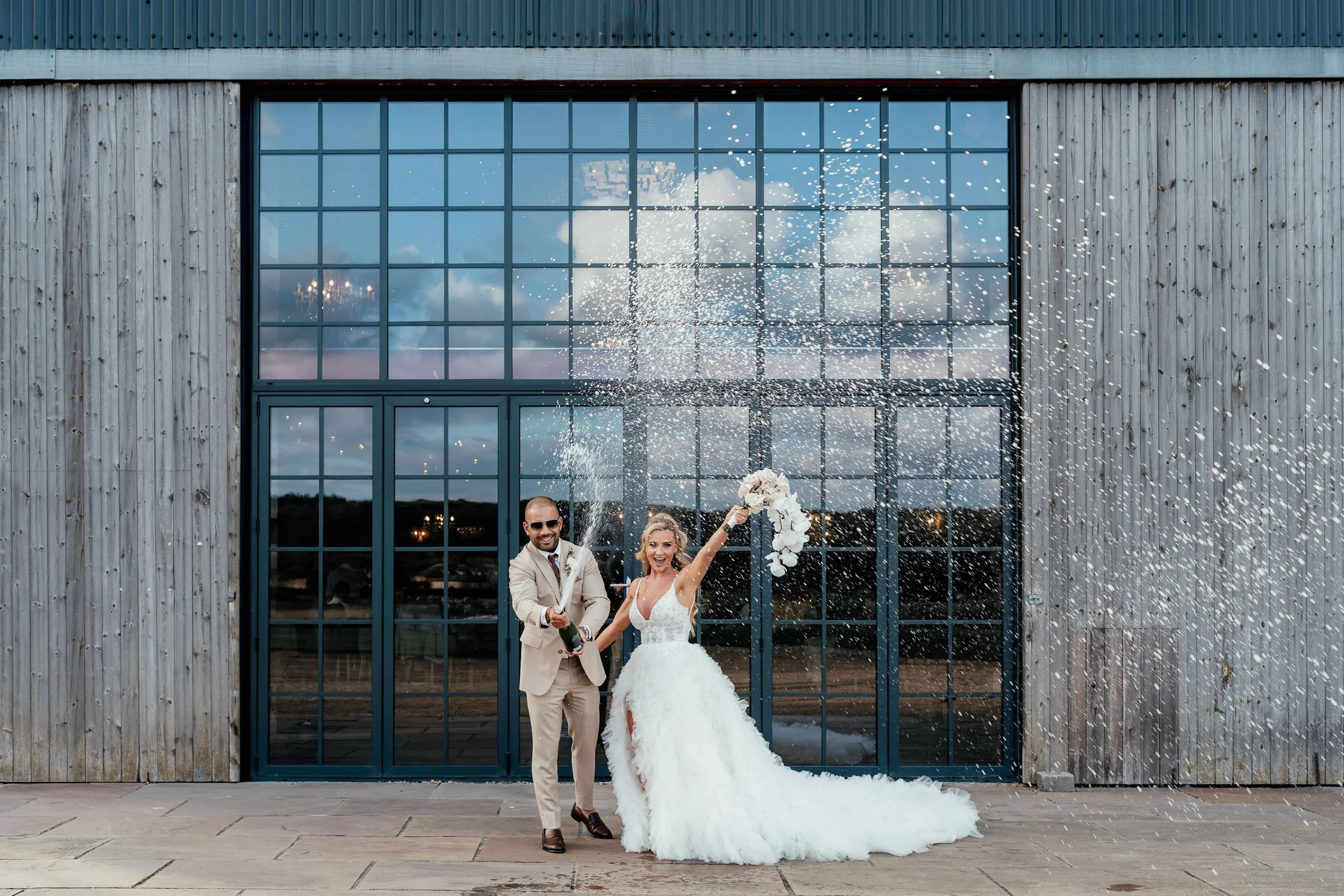 bride and groom with champagne spray outside Wharfedale grange