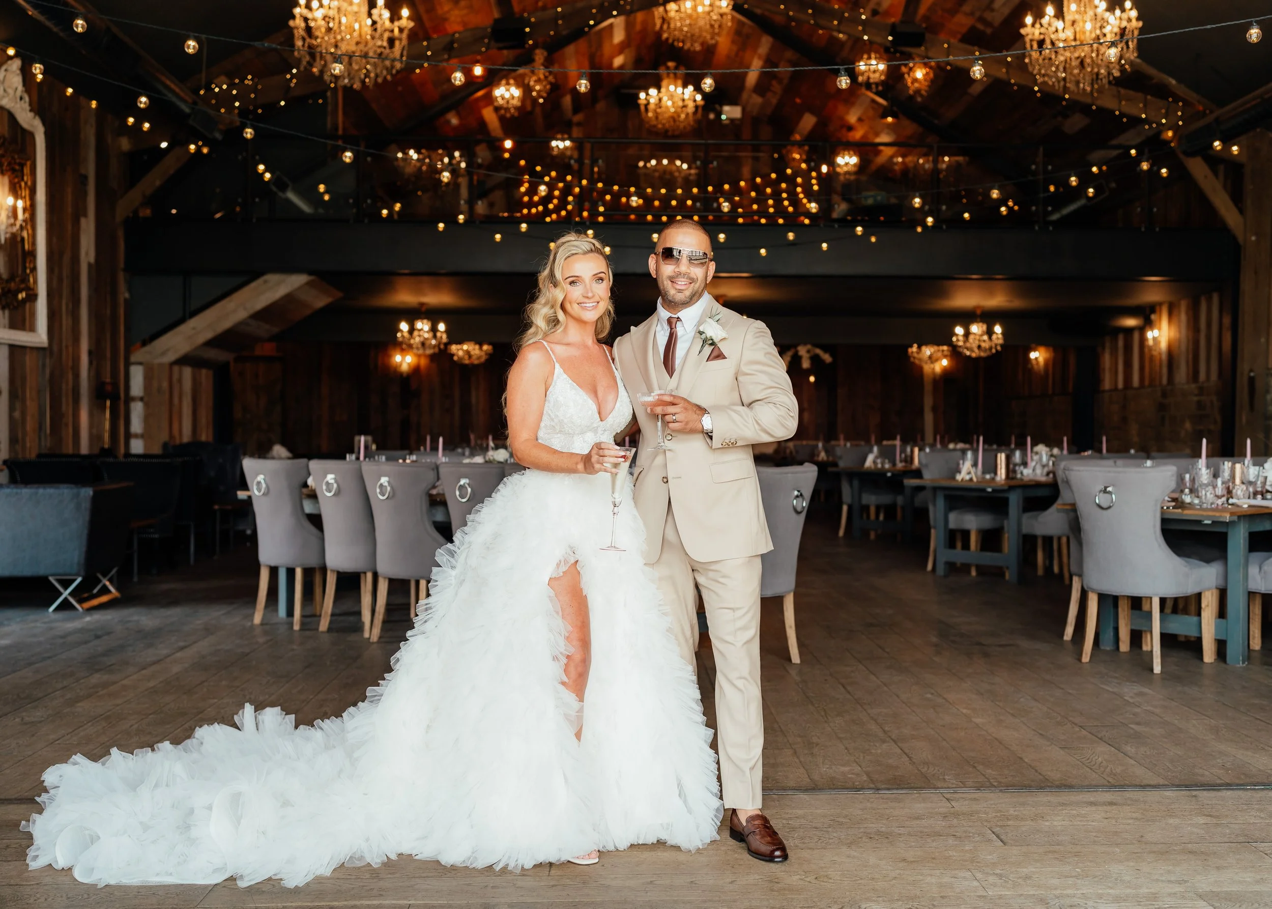 bride and groom inside Wharfedale Grange wedding venue with chandeliers and festoon lights behind