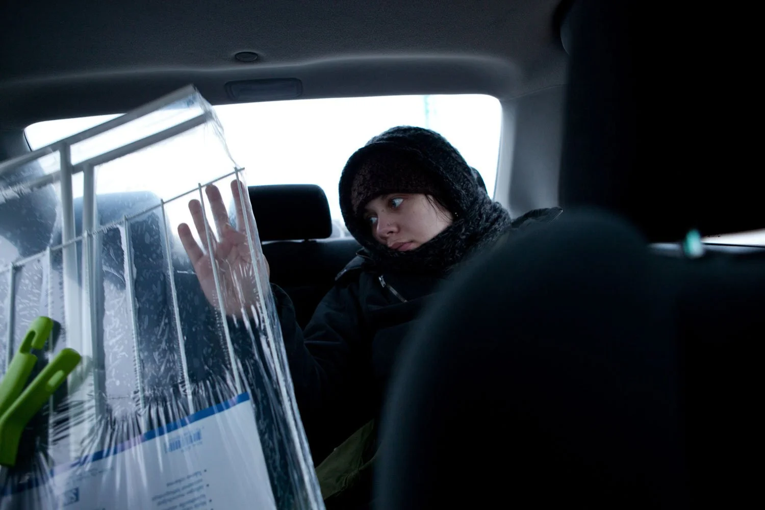 Henkilö istuu takapenkillä ja koskettaa pakkauksessa olevaa pyykinkuivaustelinettä.