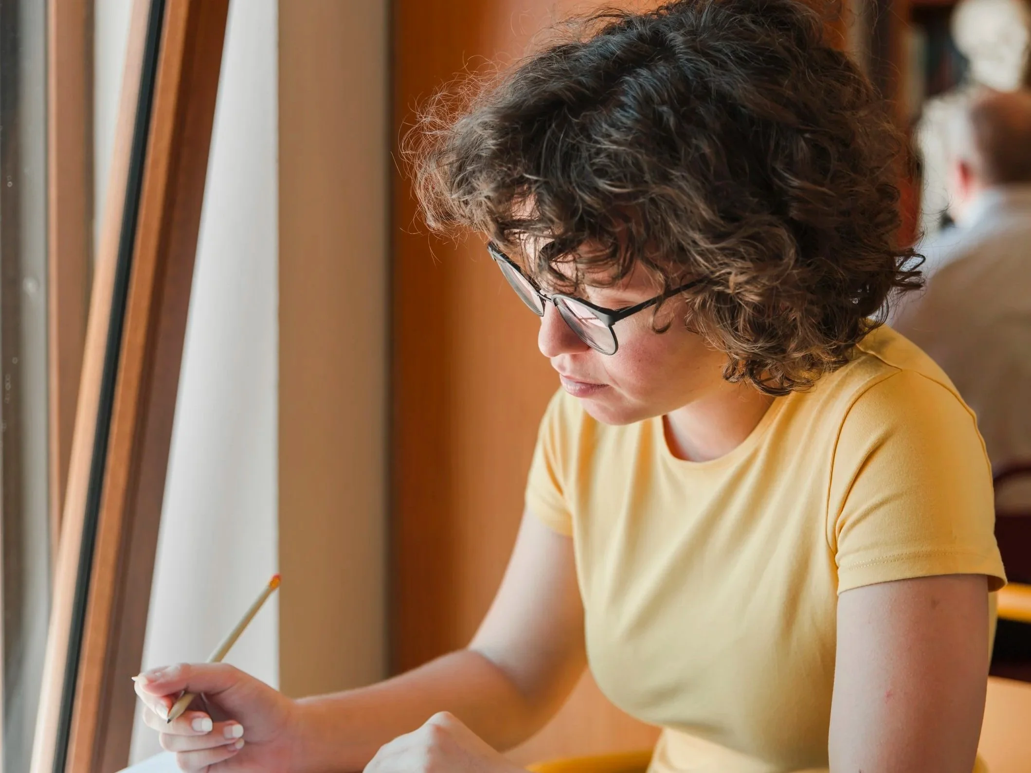 Teilnehmerin der Maßnahme Integrationsturbo U25 hat einen Stift in der Hand und schaut nach unten auf ein Papier