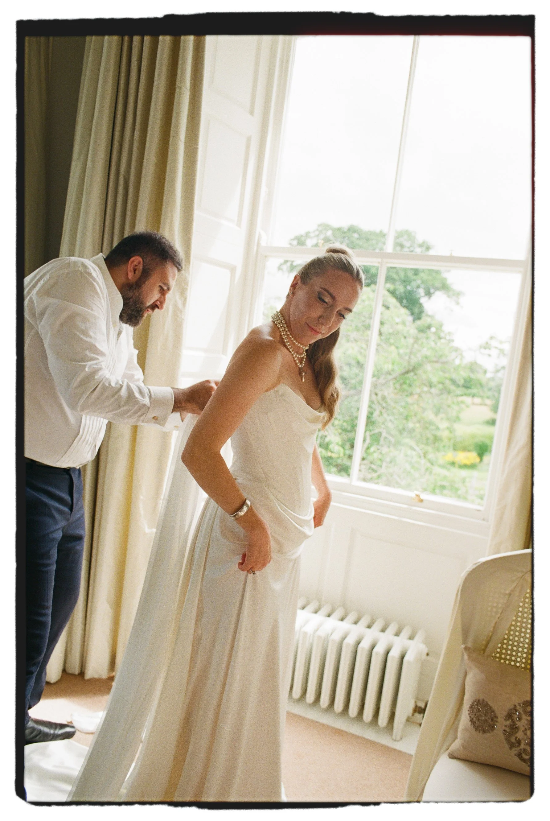 bride putting on Vivienne Westwood dress at Lartington Hall UK wedding venue bridal portrait on 35mm analogue film