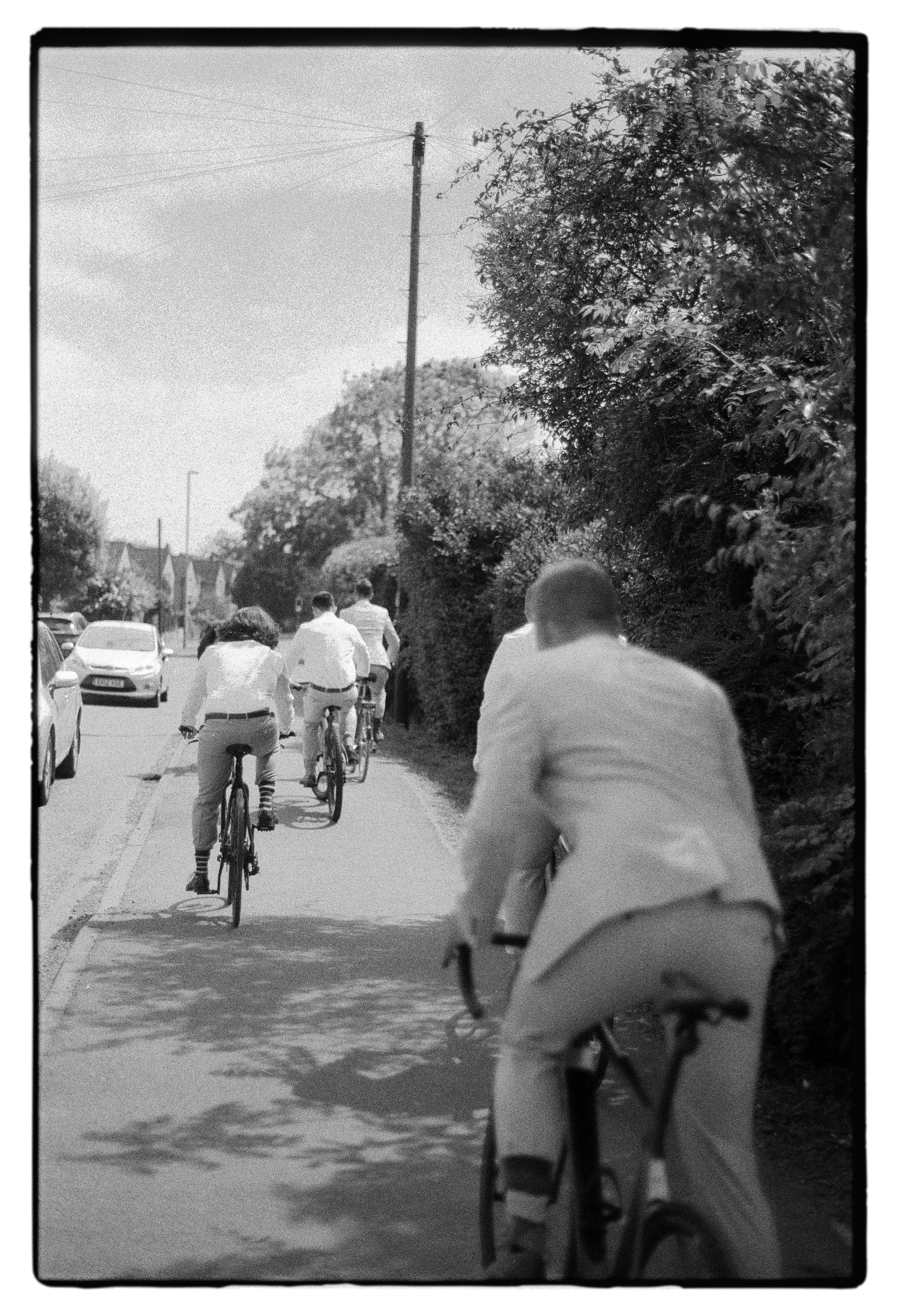 grooms biking to the wedding shot on black and white film