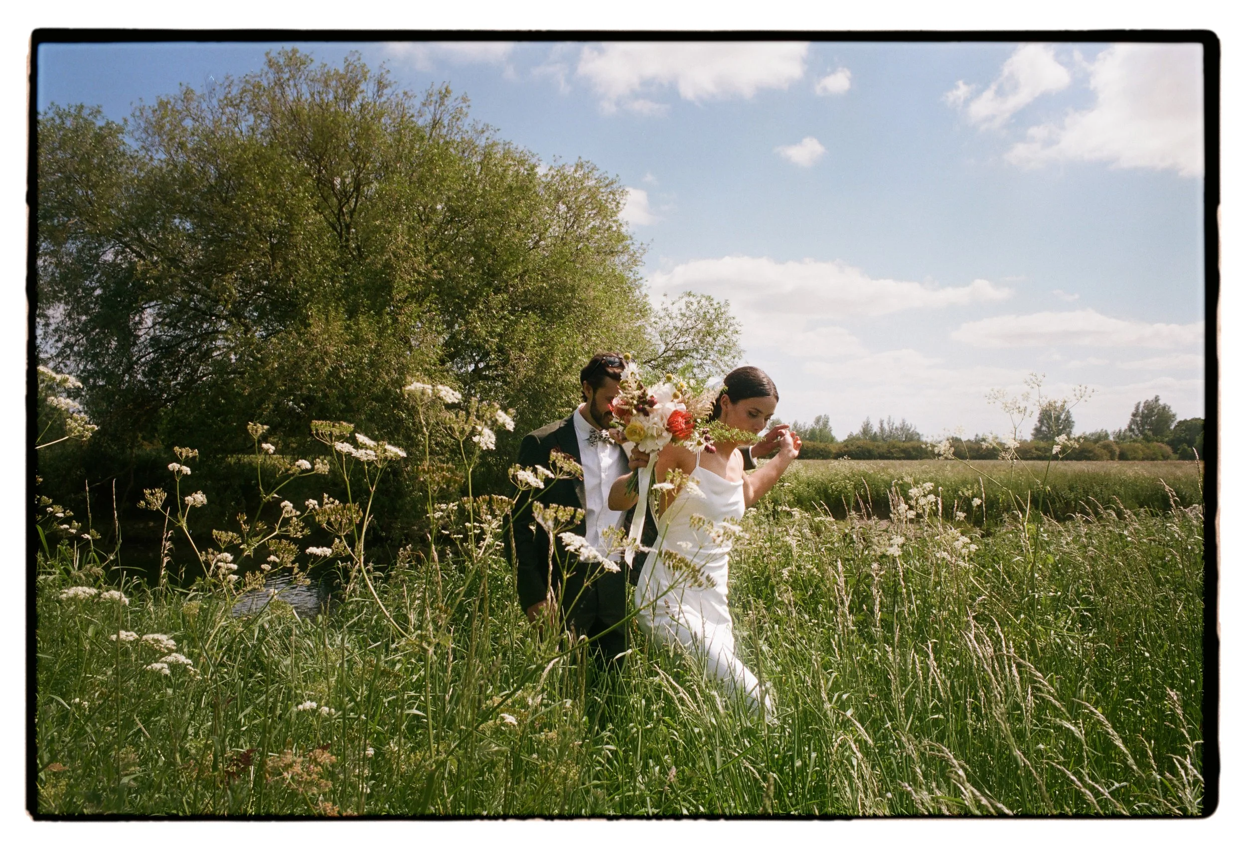 Bride and groom oxford shot on analogue 35mm wedding walking through fields