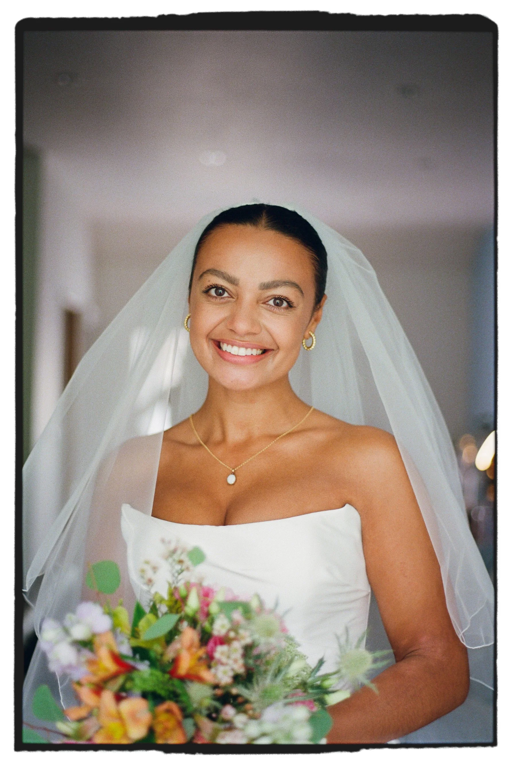Bridal portrait taken in the morning with veil in window light taken on 35mm film